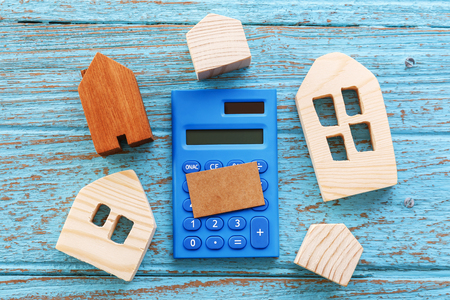 wood houses and calculator with blank brown card for housing loan concept